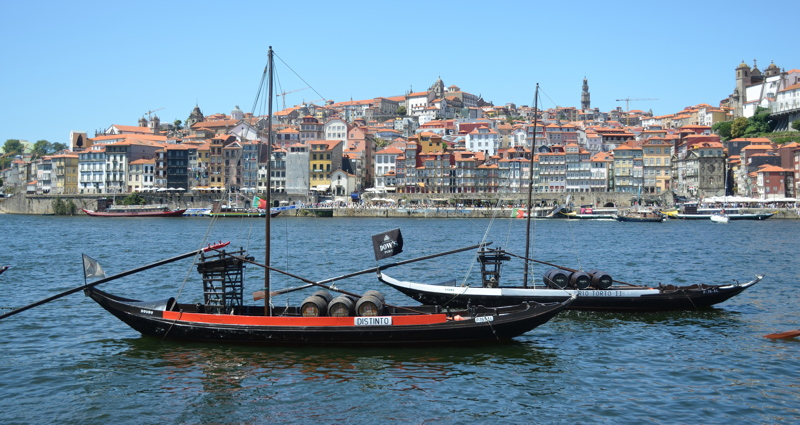 28 - Traditional Rabelo boats float on the Douro River with the historic riverside architecture of Porto and Vila Nova de Gaia in the background
